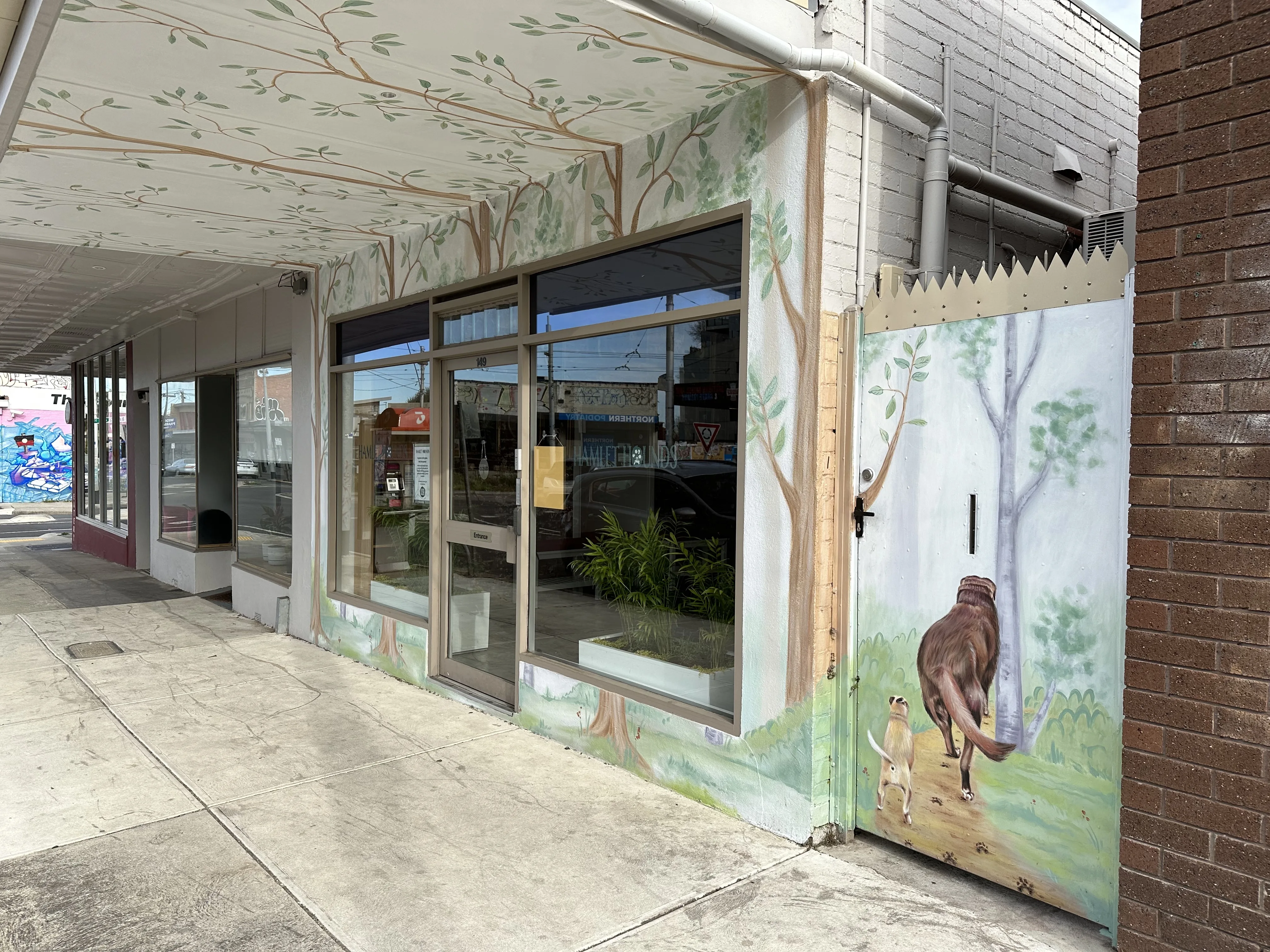 Hamlet Hounds shopfront at 149 Miller Street, Thornbury, with hand-painted gum-forest mural wrapping the corner